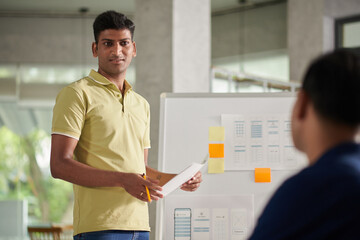 Wall Mural - smiling ux designer presenting his idea to colleagues at weekly meeting