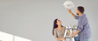 © Studio Romantic - Happy family couple changing light bulb at home. Young man and woman standing on ladder and changing modern energy-saving lightbulb in ceiling lamp. Banner, header, grey copy space wall background