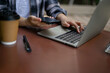 © bongkarn - Close-up image of a female freelancer remote working at the cafe, using her phone and laptop