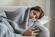 © DimaBerlin - Moody sad teen girl wrapped in plaid lying on sofa at home, using smartphone. Upset teenage kid bored at home when sick, holding mobile phone chatting in social media. Gadget addiction in teenagers