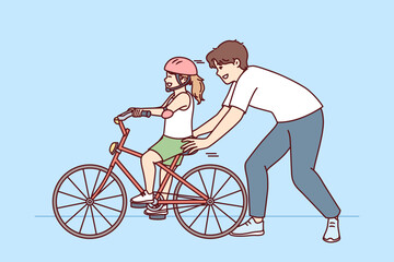 Wall Mural - Loving father helps pre-teenage daughter learn to ride bike. Happy childhood for little girl in helmet learning to ride bicycle under supervision of caring dad or brother