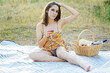 © Dan Race - Beautiful young woman at picnic outside wearing summer dress and drinking wine on a blanket
