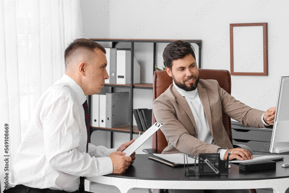 Handsome young businessman working with his colleague at table in office