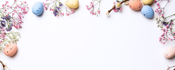 Wall Mural - Beautiful Easter banner with spring flowers and colorful quail eggs over white background. Springtime and Easter holiday concept with copy space. Top view