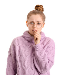 Poster - Young woman in sweater biting nails on white background