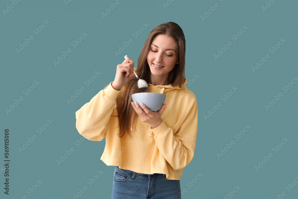 Beautiful woman with spoon and bowl on blue background
