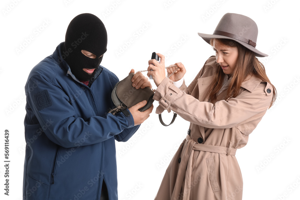 Young woman with pepper spray defending herself against thief on white background
