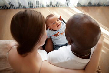 Wall Mural - Family with child. Dad holds newborn baby in his arms. Unrecognizable mother and father with son at home, rear view