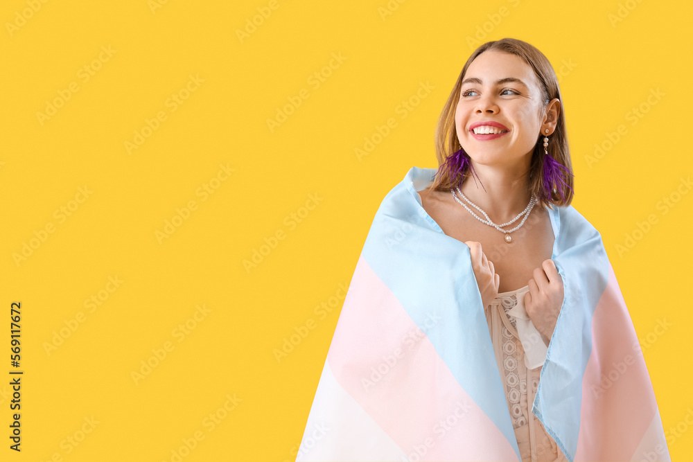 Young woman with transgender flag on yellow background
