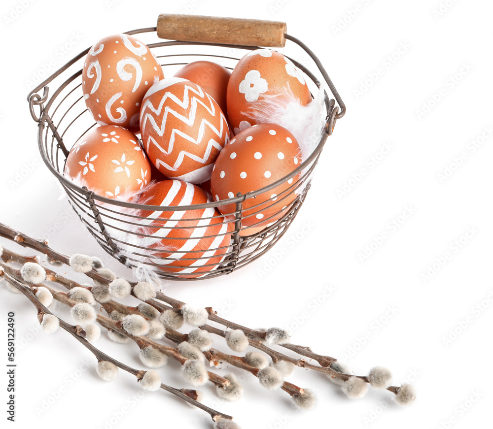 Basket with painted Easter eggs and willow branches on white background