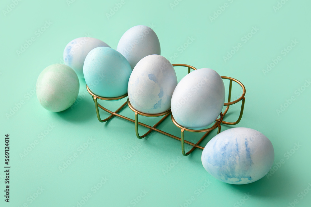 Holder with painted eggs for Easter  celebration on color background