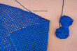 Folded blue crochet net with a hook inside of the loop and a ske