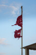 Old tattered red flag in front of the blue sky