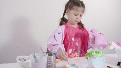 Wall Mural - Little girl painting paper mache figurines with acrylic paint for her homeschooling art project.