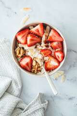 Wall Mural - Cottage cheese bowl with strawberries, cereal flakes, coconut, nuts and syrup, marble background.