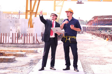  Engineer standing at construction site and use a laptop.