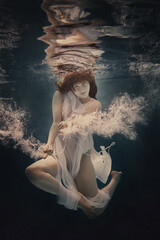 Wall Mural - Portrait of a girl in a dress floating underwater as if she were in a weightlessness