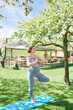 © annanahabed - Outdoor portrait of happy young pregnant woman practicing youga in spring garden under blooming apple trees, healthy lifestyle