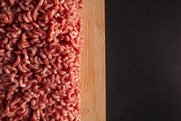 Ground mince raw meat on wooden board, black background, copy space