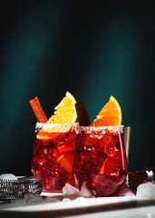 Wall Mural - Negroni mezcalito alcoholic cocktail with mezcal, vermouth, bitters, herbal liqueur, orange, cinnamon and ice. Dark background, hard light and shadow pattern