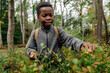© Maskot - Curious boy picking berries from plants in forest during vacation