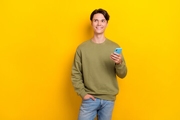 Canvas Print - Photo of cheerful minded person hold telephone look empty space isolated on yellow color background