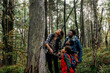 © Maskot - Mother looking up while standing near tree with family during vacation in forest
