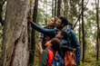 © Maskot - Father showing tree while talking with family during vacation in forest
