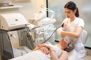 Wall Mural - Doctor with Ultrasonic scraber doing procedure of ultrasonic cleaning of female client neck at beauty salon.