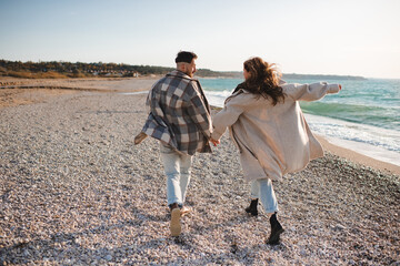 Wall Mural - Happy love couple running at sea shore wear casual coat and denim pants at beach outdoor. Carefree lifestyle concept.