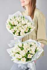 Wall Mural -  Florist woman creates beautiful two bouquet of bouquets of spring cream tulips. European floral shop concept. Handsome fresh bunch. Education, master class and floristry courses. Flowers delivery.