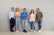 © Studio Romantic - Confident toung team. Portrait of group of different positive smart young people on gray wall background. Men and women in stylish smart and casual clothes stand in row and smile looking at camera.