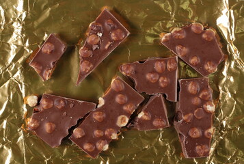 Canvas Print - Chocolate bars set with hazelnut, pieces on golden aluminum foil, top view