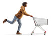 © Ljupco Smokovski - Full length profile shot of a young african american man running with an empty shopping cart