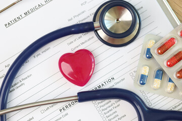 Wall Mural - Patient medical history form with red heart, stethoscope and pills packs close up.