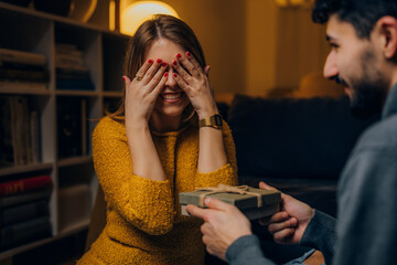 Wall Mural - Woman covers her eyes before receiving a present from her boyfriend