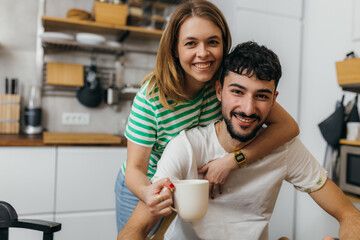 Wall Mural - Young couple in the kitchen looking at the camera