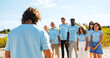 © ihorvsn - A volunteer mentor planning and instructing multiethnic people on voluntary activity. Group of volunteers listening to the leader's intructions and raising hands up. Ecology, pollution concept.