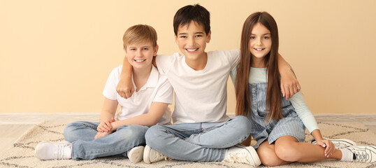 Poster - Happy little friends sitting near beige wall in room