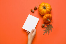 Woman Holding Paper Sheet, Pumpkins, Acorns And Leaf On Red Background