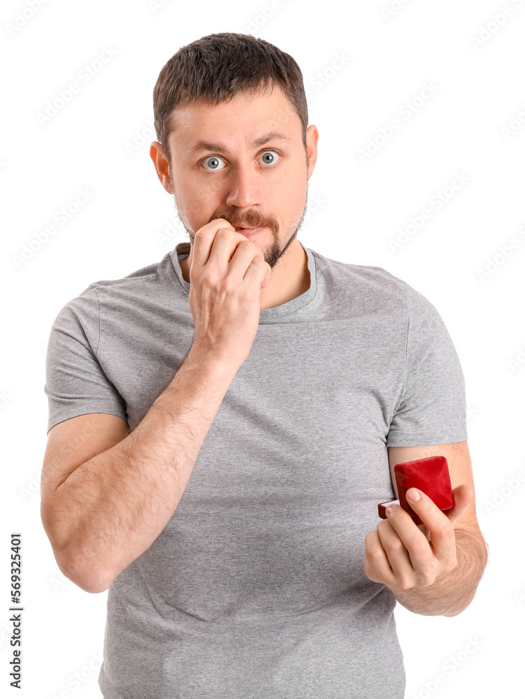 Handsome man with engagement ring biting nails on white background