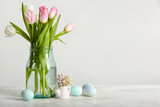 Fototapeta Kawa jest smaczna - Vase with beautiful tulip flowers and Easter eggs on light background