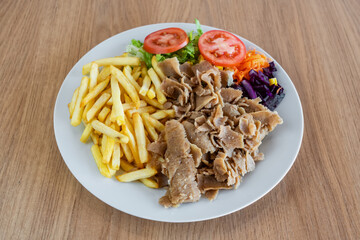 Kebab on a plate with fried potato salad and vegetables.