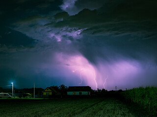 Wall Mural - lightning storm over a rural area lits up the sky at night