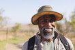 © Wavebreak Media - Portrait of smiling bearded african american senior man wearing hat hiking in forest under clear sky