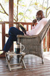 © Wavebreak Media - Side view of bald african american senior man reading book while sitting on chair in balcony