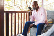 © Wavebreak Media - African american senior man sending voicemail over mobile phone while sitting on chair in balcony