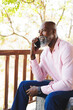 © Wavebreak Media - Bald african american senior man talking over mobile phone while sitting in balcony at log cabin