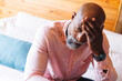 © Wavebreak Media - Close-up of stressed bald african american senior man with head in hand sitting on sofa in log cabin
