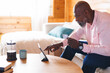© Wavebreak Media - Bald african american senior man using digital tablet by french press and mug on tablet in log cabin